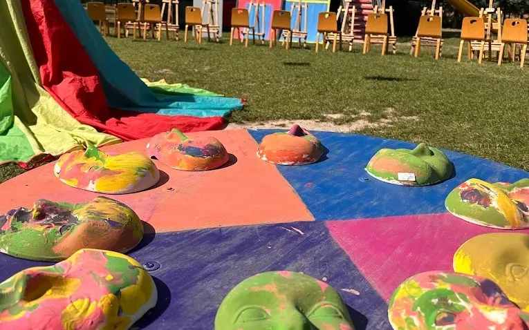 Açık hava atölyesinde çocukların boyadığı maskeler ve tabaklar