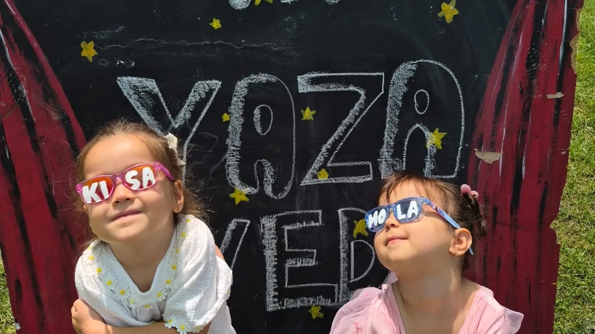 Yaz etkinliğinde renkli parti gözlükleriyle poz veren iki çocuk