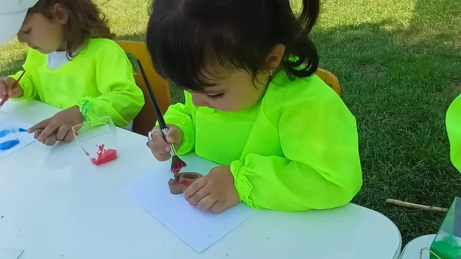 Açık hava atölyesinde önlükleriyle resim yapan iki çocuk